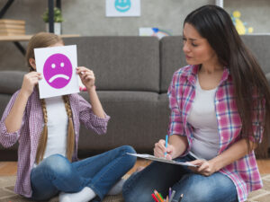 female-psychologist-taking-notes-looking-girl-covering-her-face-with-sad-emotion-card.jpg